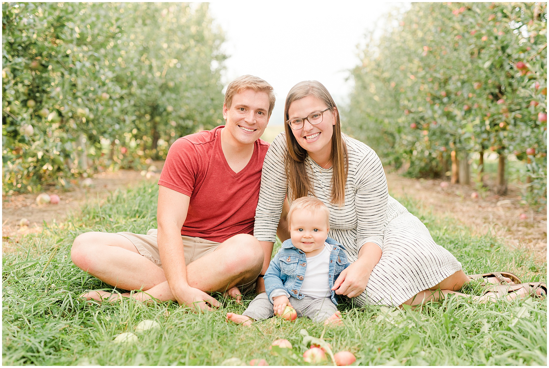 family photographers with child sitting in apple orchard